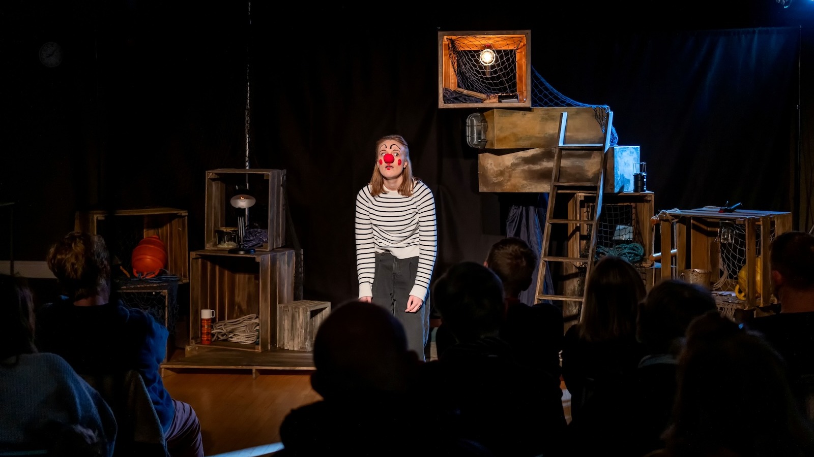 A woman wearing a red nose looking sad on stage
