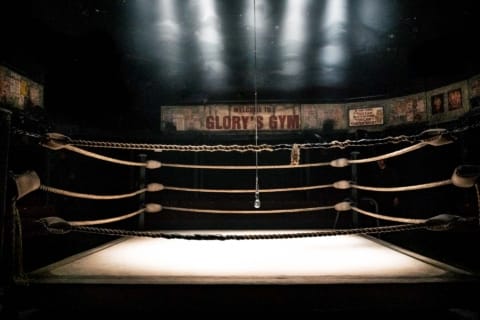 An empty wrestling ring in a gym with microphone hanging from ceiling