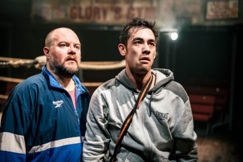 A wrestler in gym clothes looking despdondent with his coach