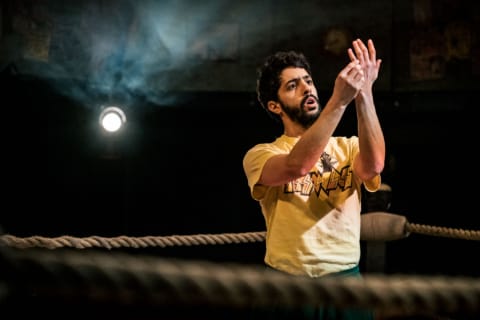 A wrestler gazing at his hands in a gym ring