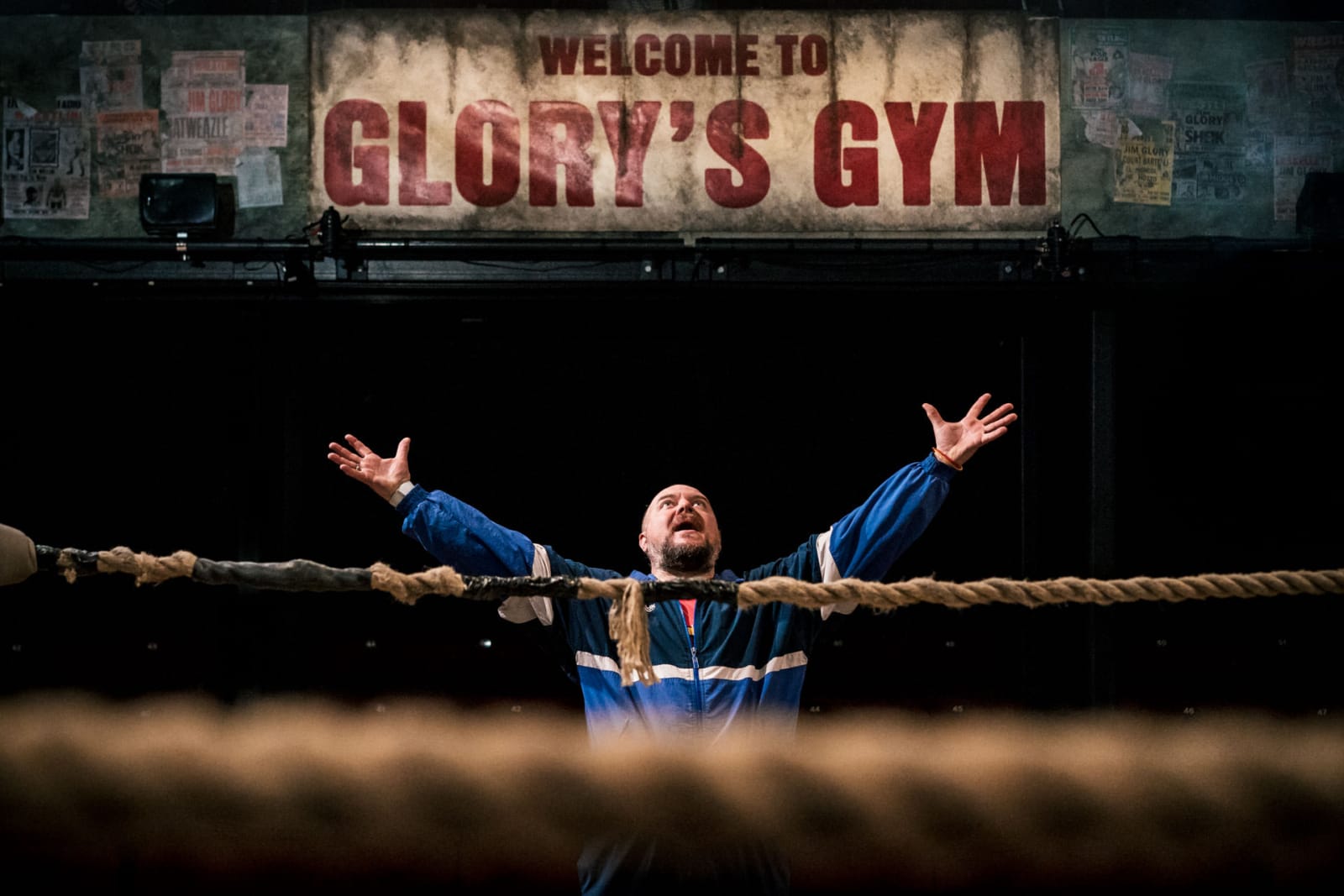 A wrestling coach with heads spread proudly under the sign of Glory's Gym