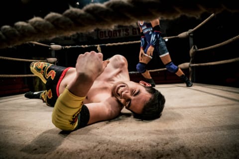 A wrestler lying on the floor of a ring in pain