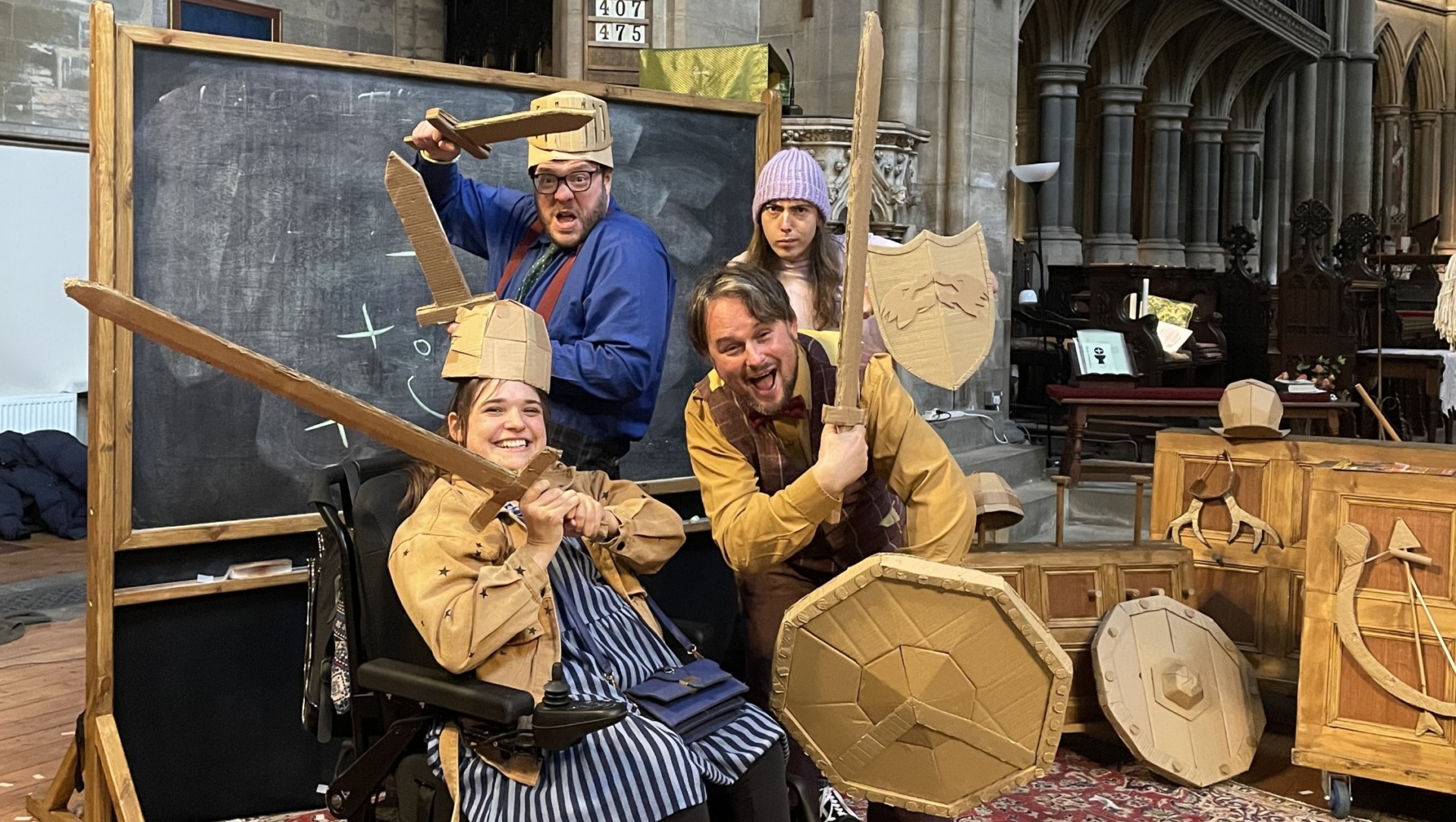 Zoe in her wheelchair with the Rubbish Shakespeare Company wielding cardboard weapons