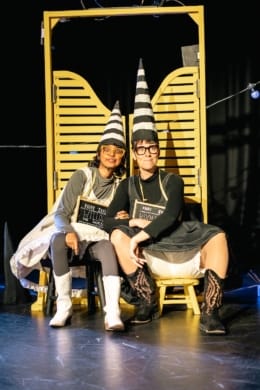 Two girls in dunce's outfits leaning against a saloon door