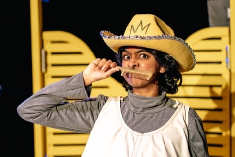 A girl in a stetson holding a comb above her lip like a moustache
