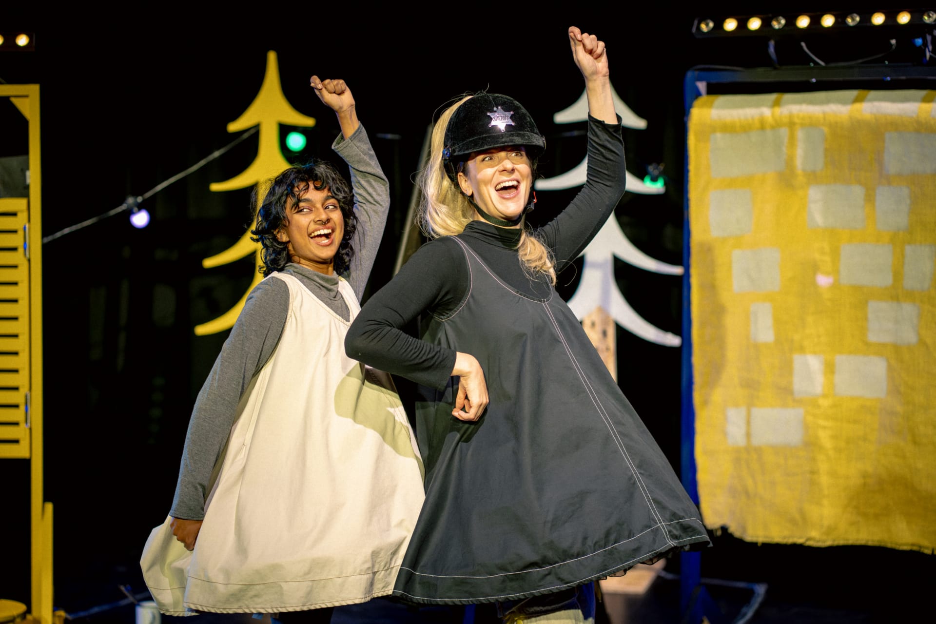 Two girls in pinafores dancing as if lassoing