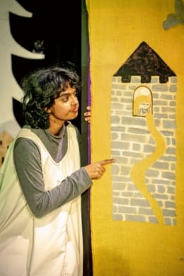 A girl dressed in a pinafore pointing to Rapunzel drawn in her tower