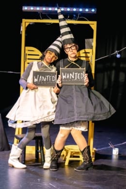 Two girls in dunce's outfits leaning against a saloon door
