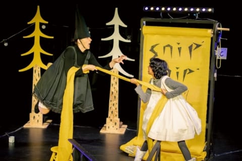 A girl and witch pulling a long piece of yellow fabric between them