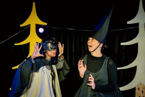 A girl in a black mask frightening a witch