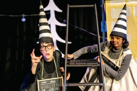 Two girls in dunce's outfits swinging from a stepladder