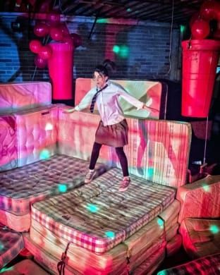 A woman jumping on a bed.