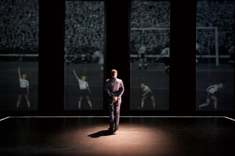 A man watching a football game projected onto the back screen.