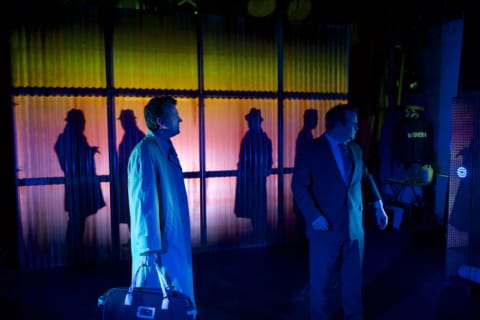 Two men talking to eachother, in a space with others around them.
