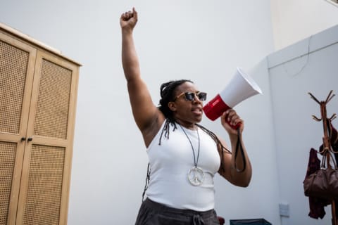 Alicia with a fist in the air whilst shouting into a megaphone