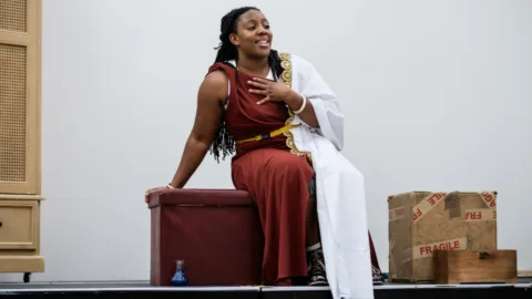 Alicia in ancient costume sat on a trunk