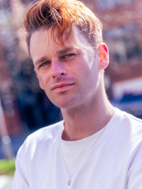 Alex in a white t-shirt looking serious