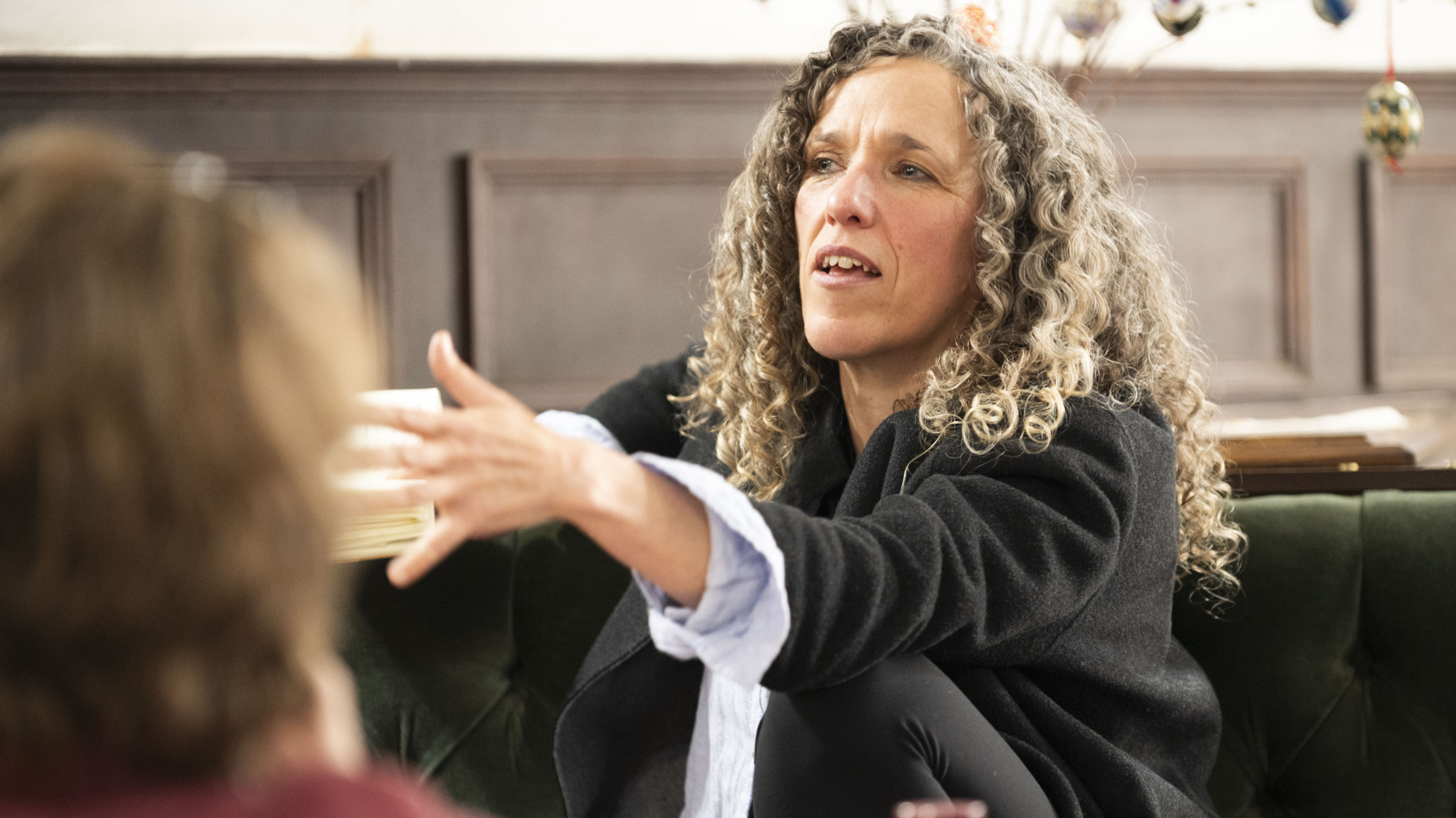 A woman with grey curly hair reaching to an audience